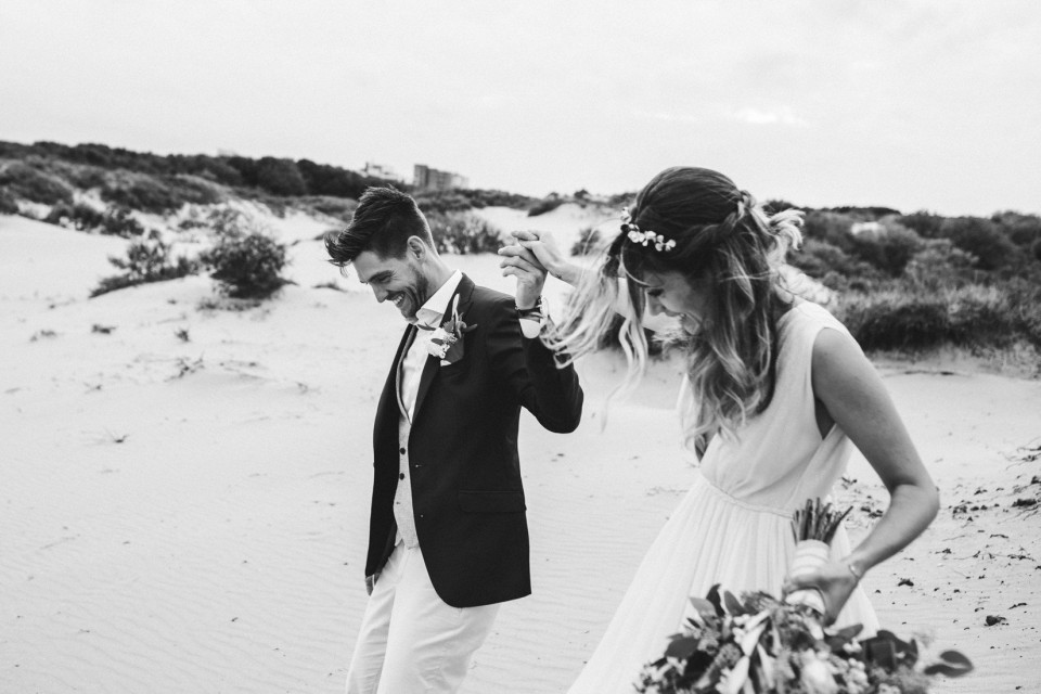 een bruid en bruidegom lopen door het zand