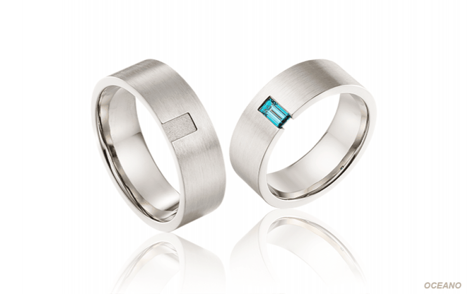 twee trouwringen met blauwe en witte diamanten