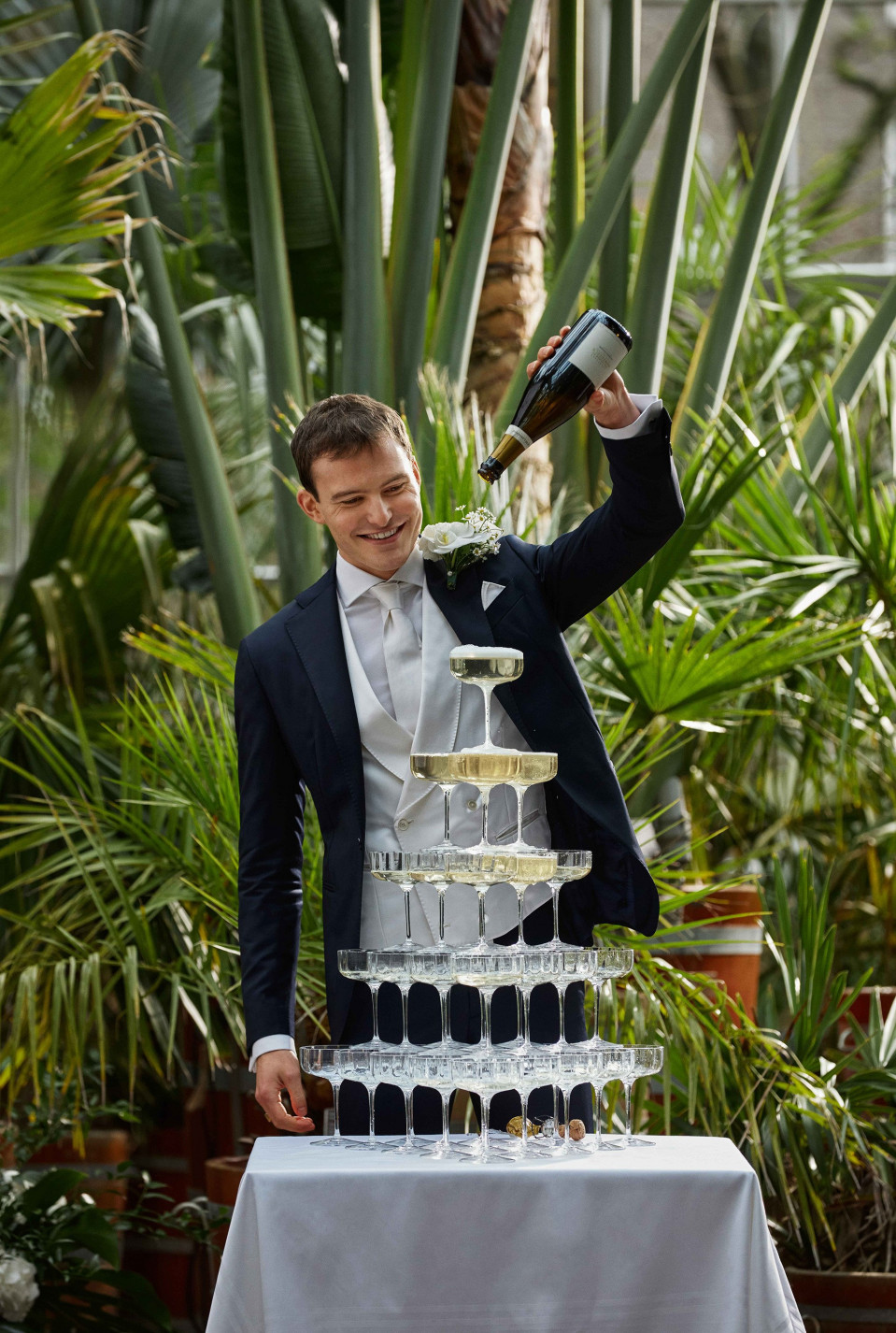 een man in pak schenkt champagne in een hoge taart