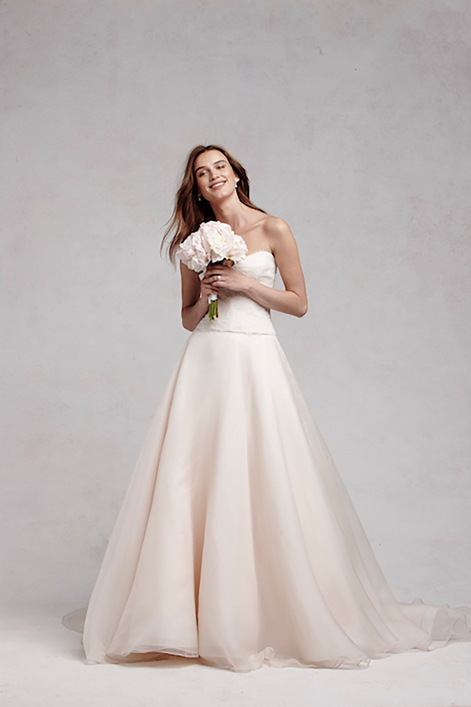 een vrouw in een strapless trouwjurk poseert voor een foto