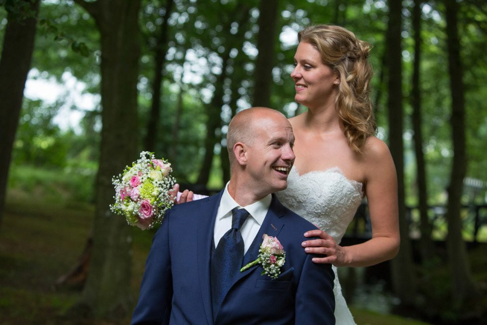 een bruid en bruidegom glimlachen in het bos