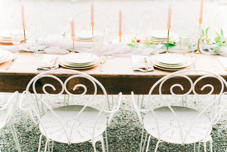 een rustieke tafel met witte stoelen en een kaars