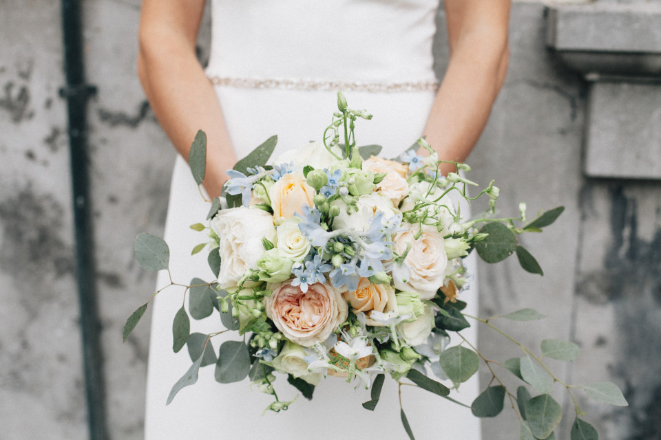 een bruid die een boeket van witte en blauwe bloemen vasthoudt
