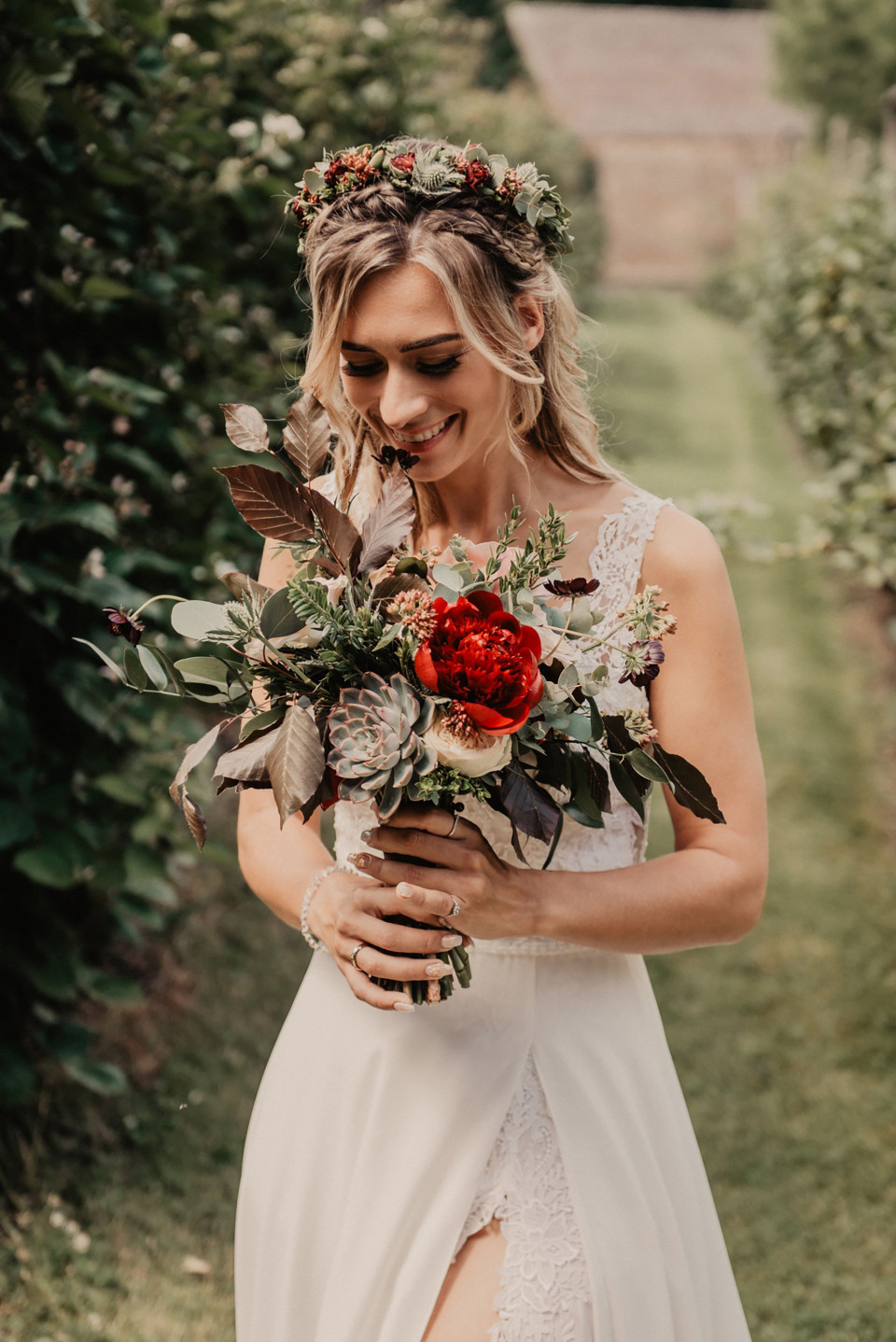 een bruid in een witte jurk die een boeket rode en witte bloemen vasthoudt