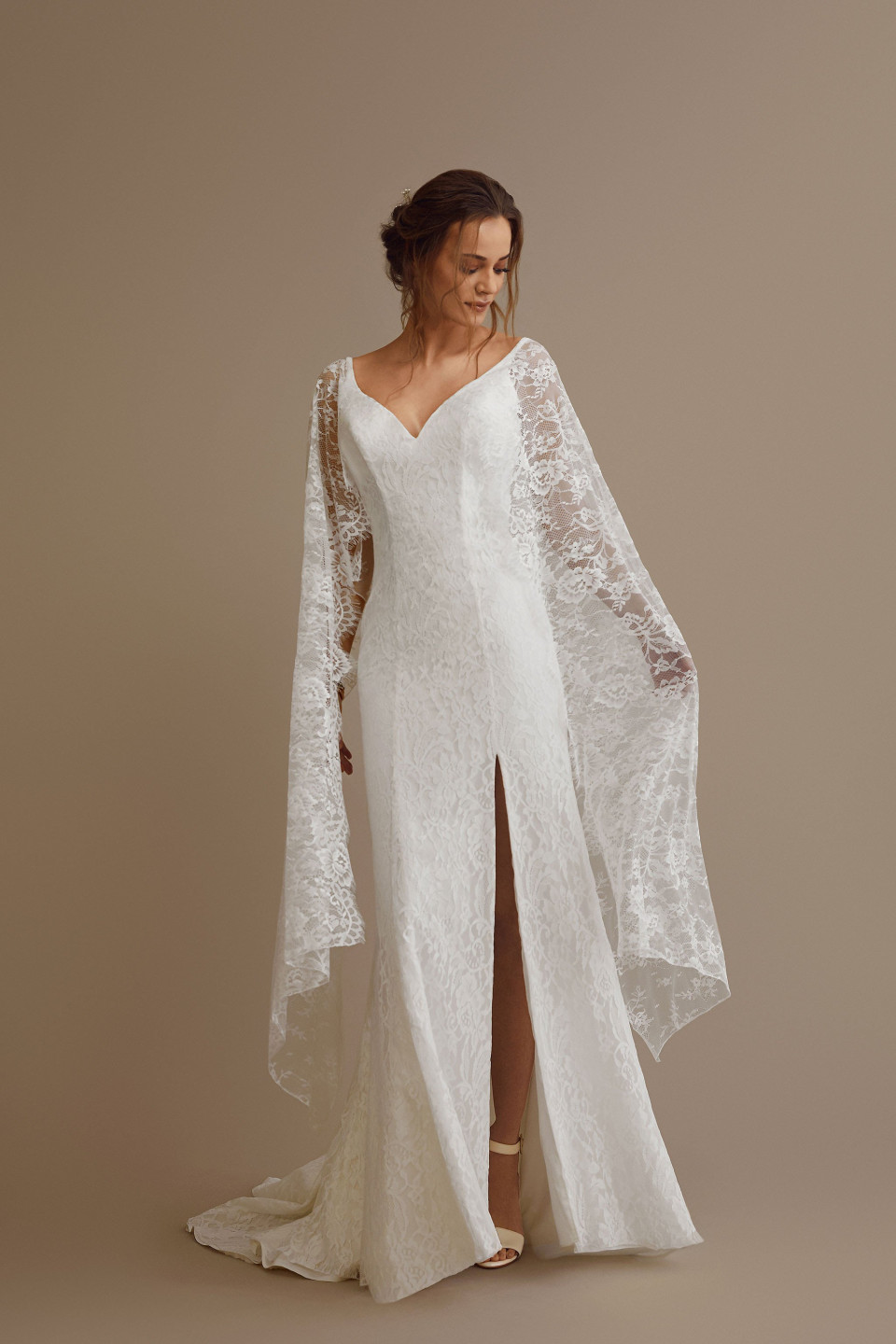 de bruid draagt een witte kanten trouwjurk met een cape
