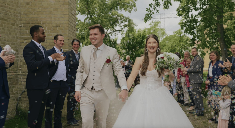 een bruid en bruidegom die de gang aflopen omringd door confetti