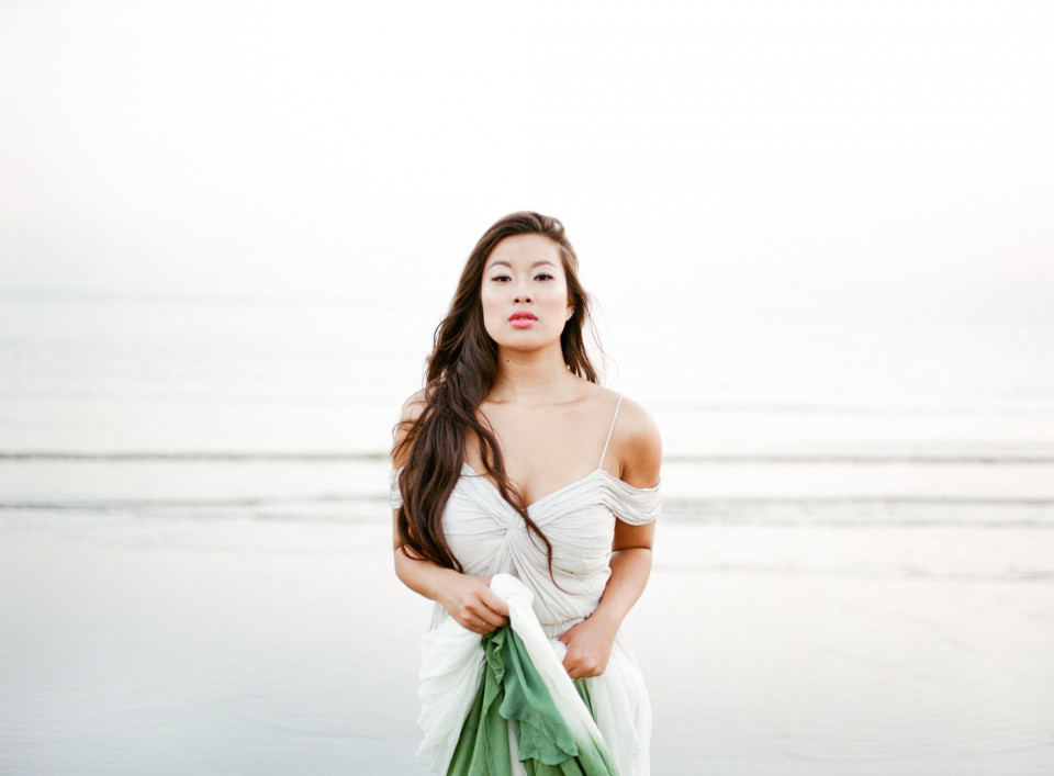 een vrouw in een witte jurk die op het strand staat