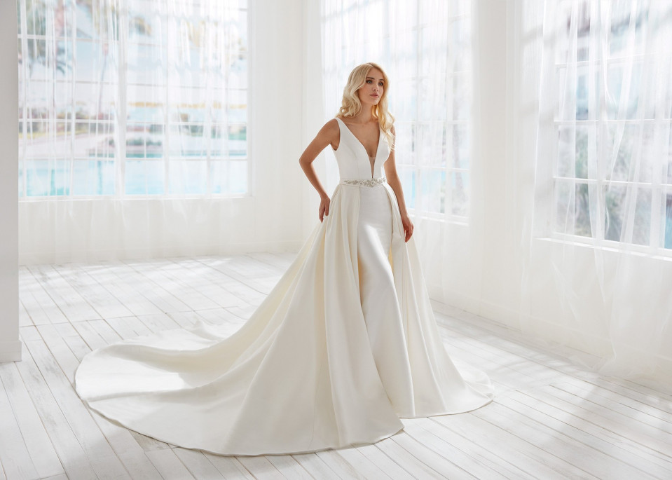 de bruid draagt een witte jurk met een diepe v-hals