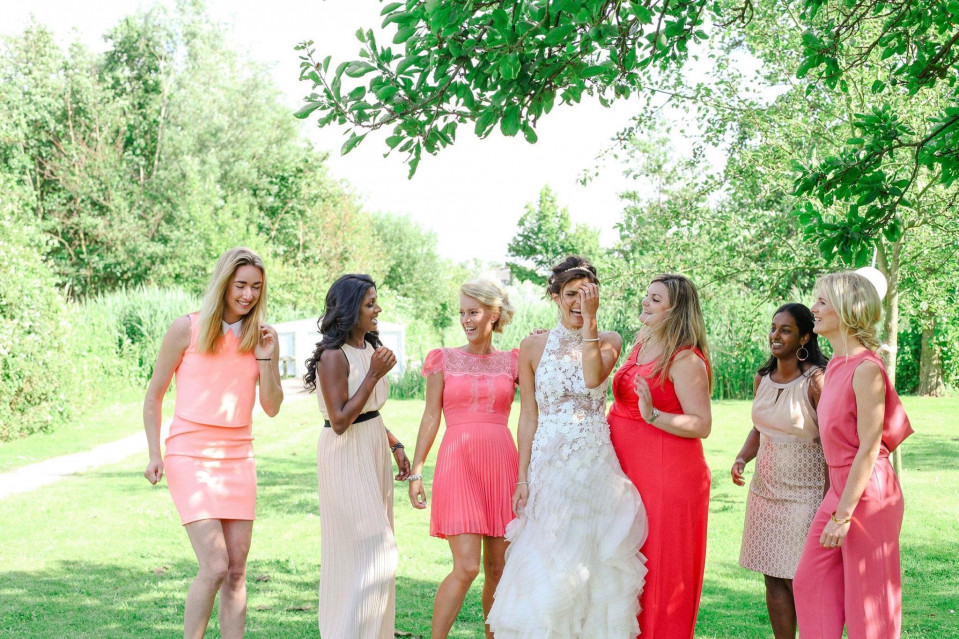 bruidsmeisjes in koraalkleurige jurken en witte schoenen