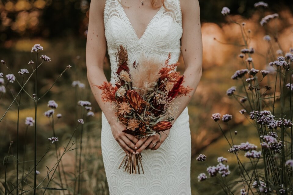 een vrouw in een trouwjurk die een boeket bloemen vasthoudt