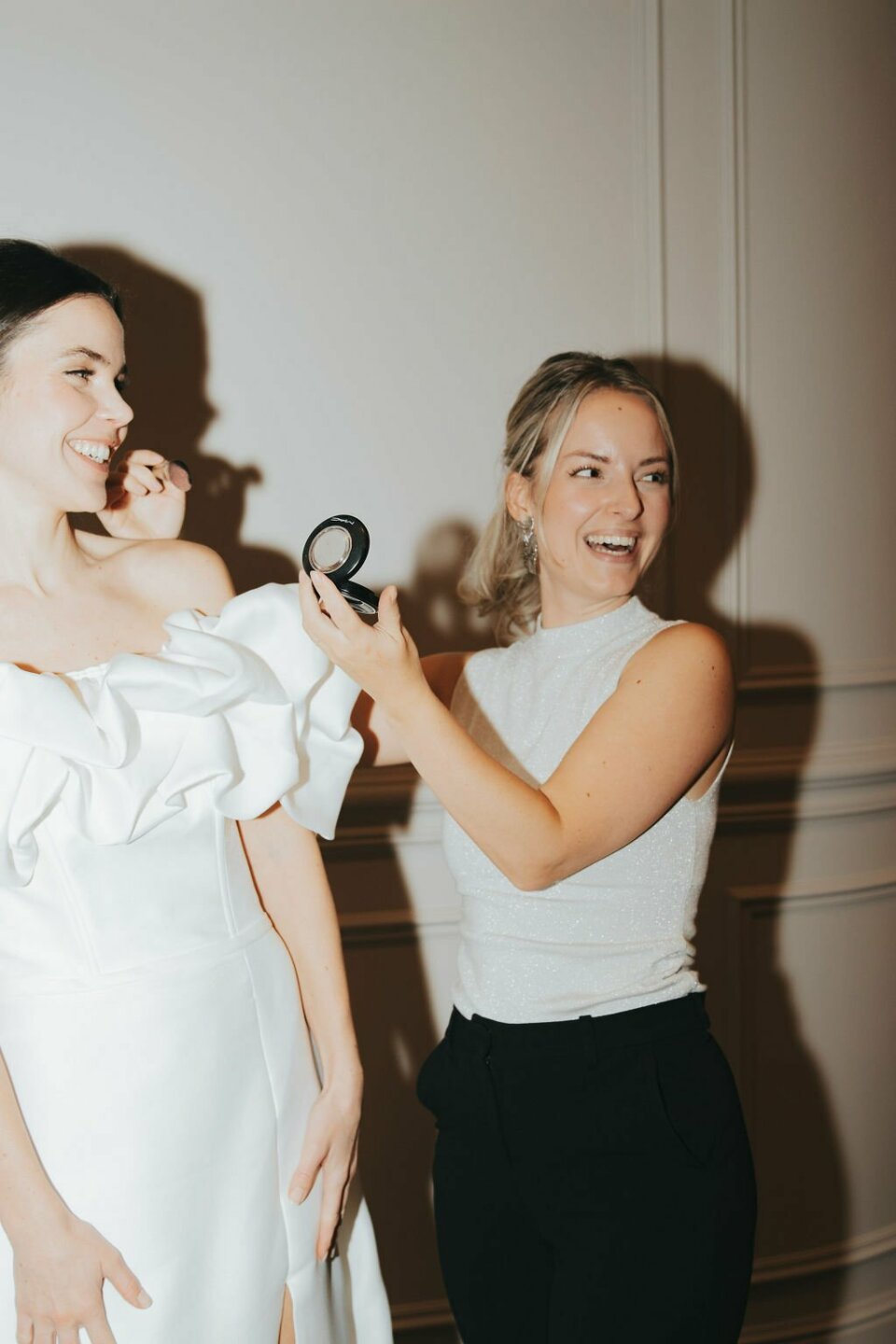 een vrouw in een witte jurk die het haar van een andere vrouw borstelt