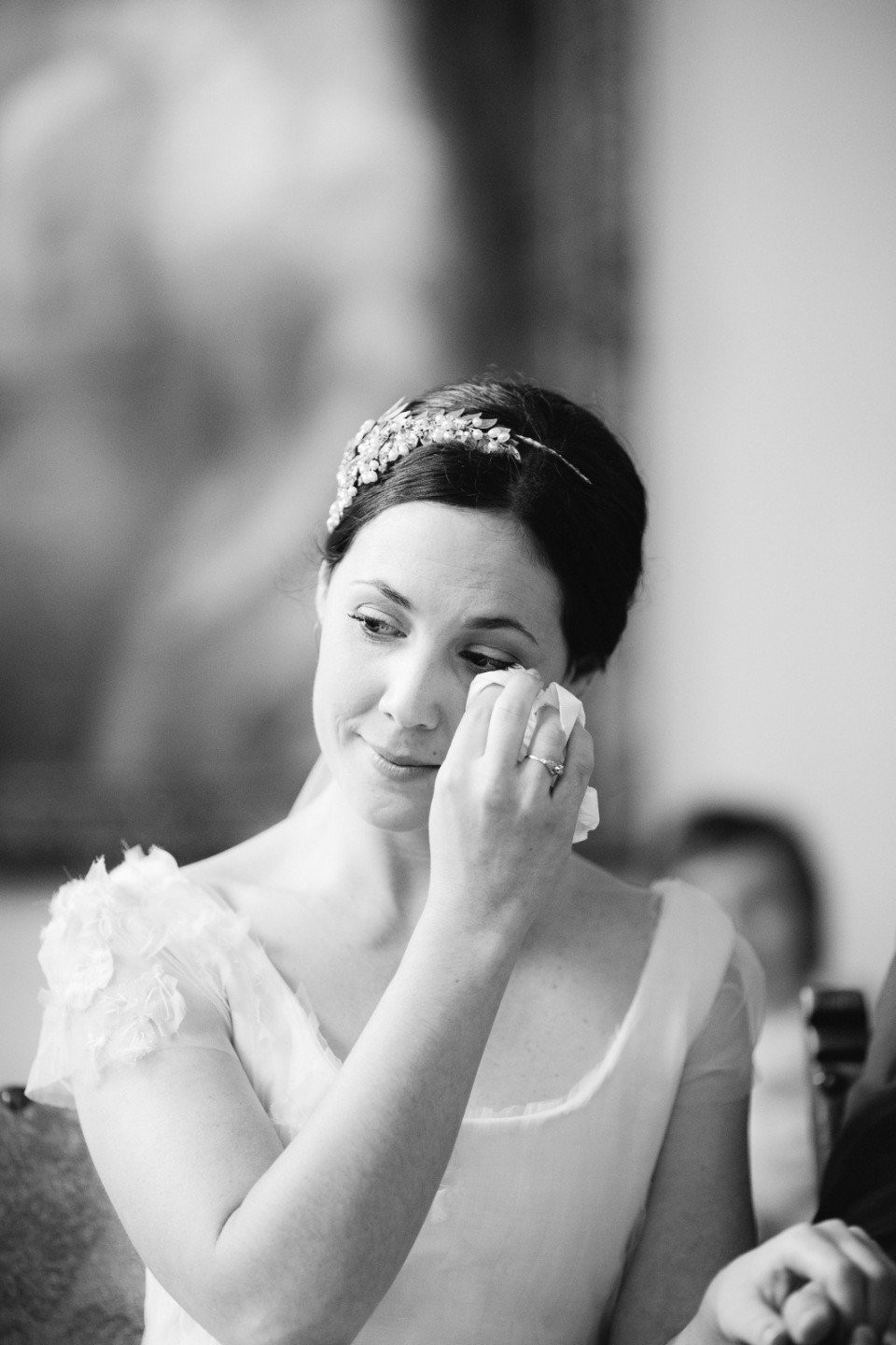 een bruid veegt haar ogen af terwijl ze aan een tafel zit