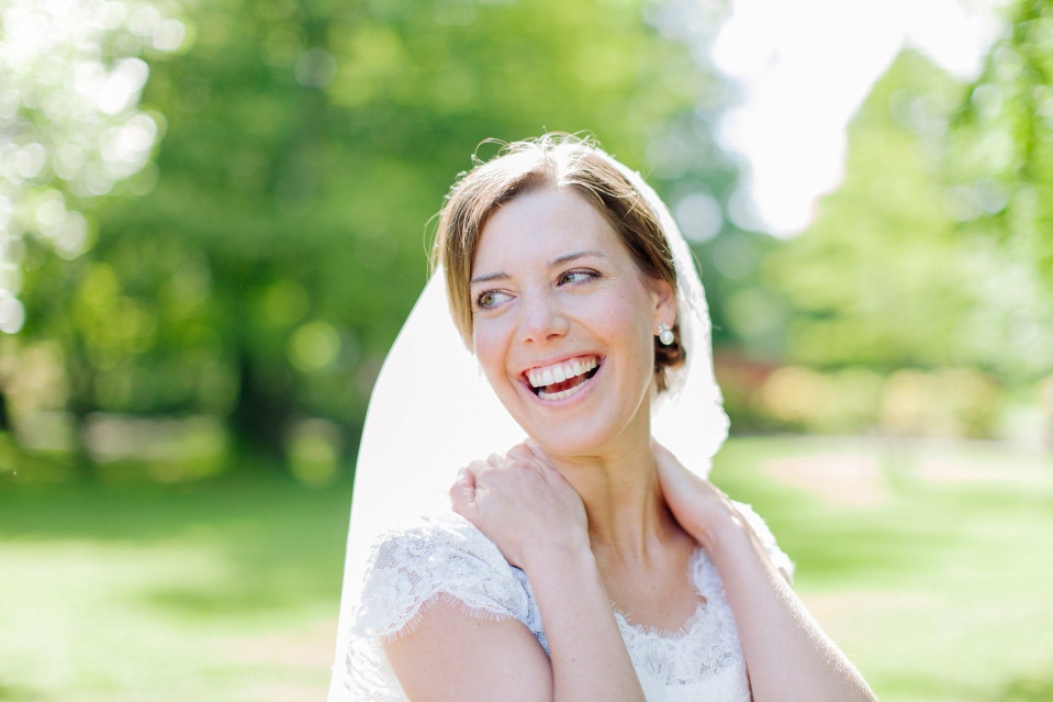 een lachende bruid in een trouwjurk in het park