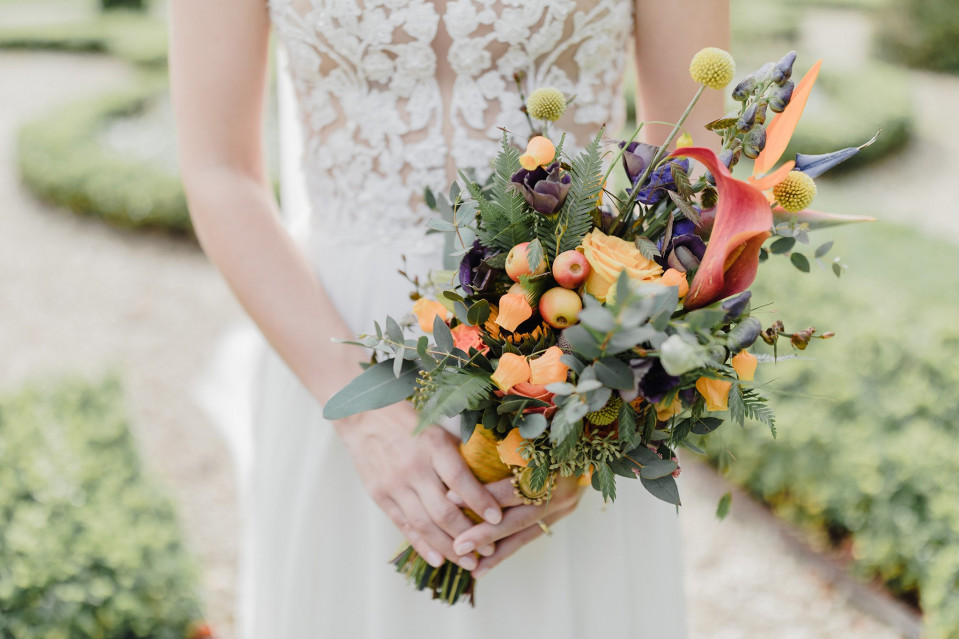 een bruid die een boeket bloemen vasthoudt in een tuin