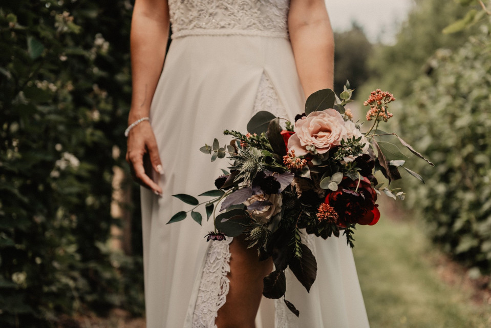 een bruid die haar boeket vasthoudt in de wijngaard
