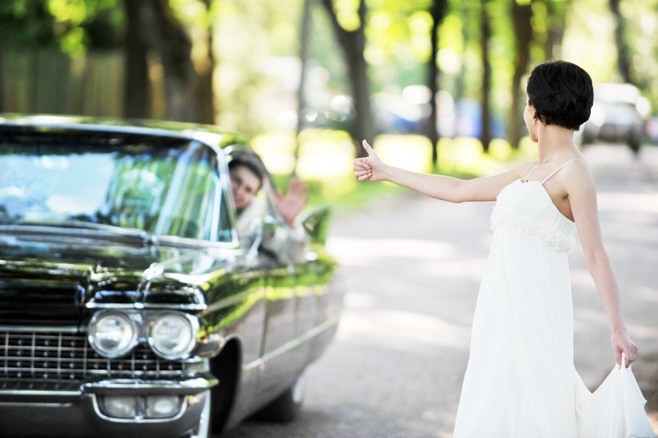een bruid en bruidegom staan naast een auto
