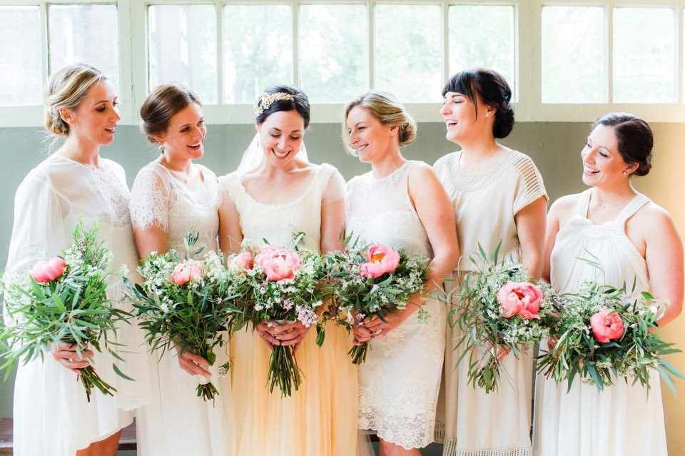 bruidsmeisjes in witte jurken met roze bloemen
