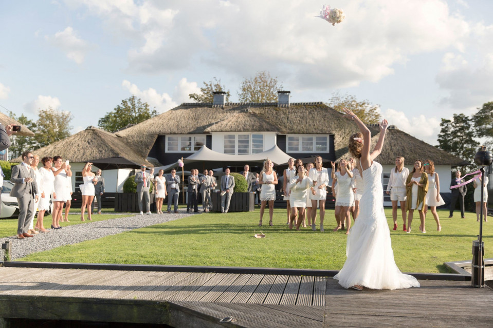 een bruid die een boeket bloemen in de lucht gooit