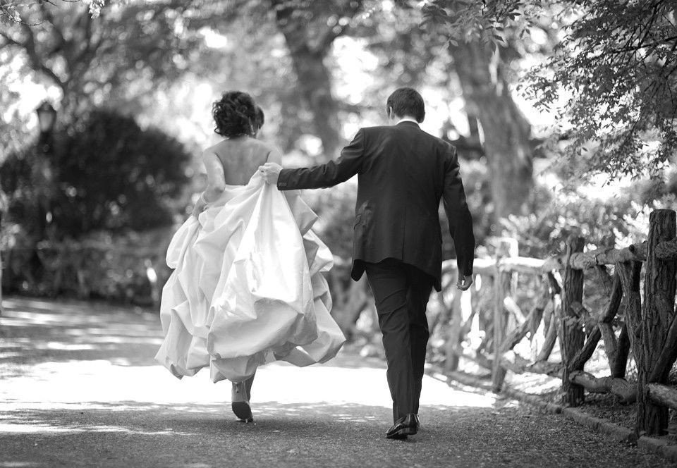 een zwart-wit foto van een bruid en bruidegom die langs een pad lopen