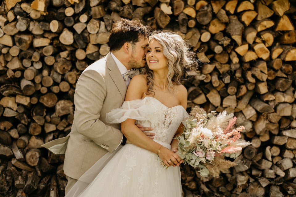 een bruid en bruidegom die kussen voor een stapel hout