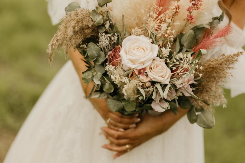 een vrouw in een trouwjurk die een boeket bloemen vasthoudt