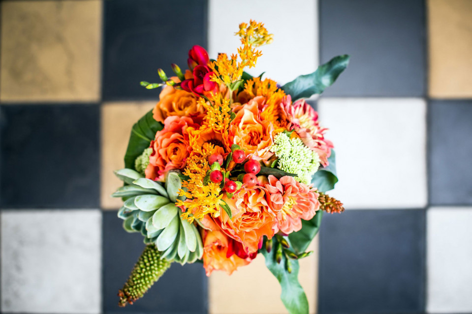 een boeket van oranje en gele bloemen op een zwart-wit geruite vloer