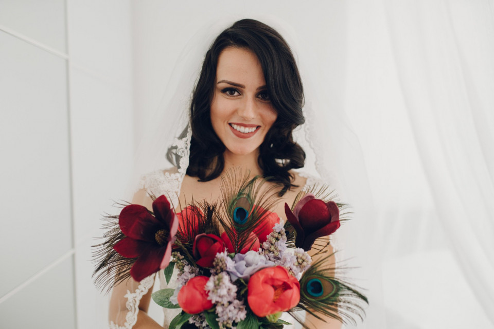 een bruid die een boeket rode en witte bloemen vasthoudt