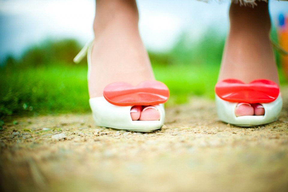 de voeten van een vrouw in witte schoenen met rode harten