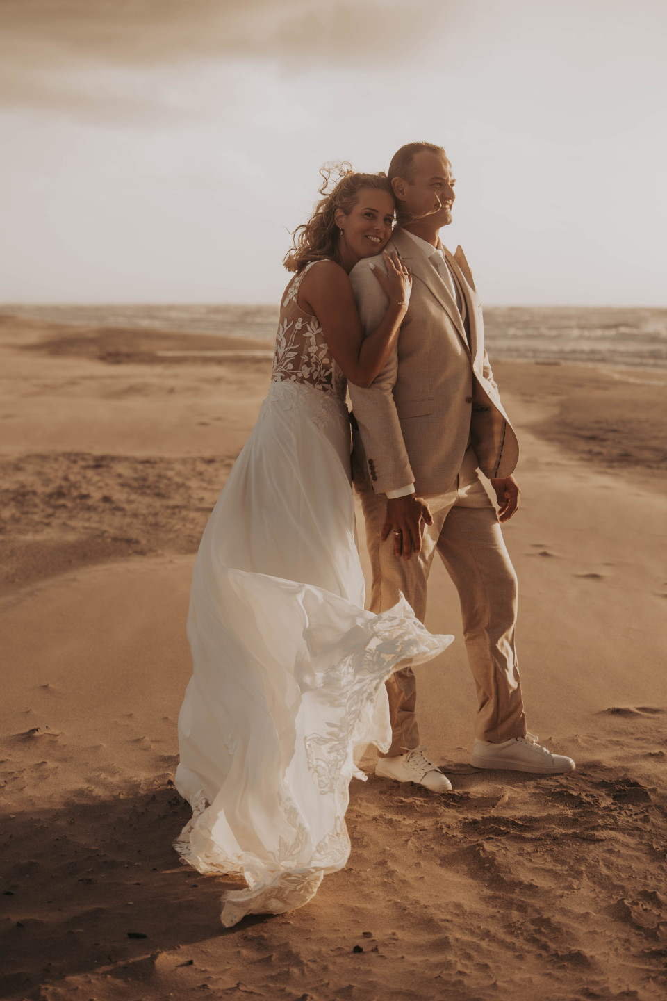 de bruid en bruidegom die samen op het strand lopen