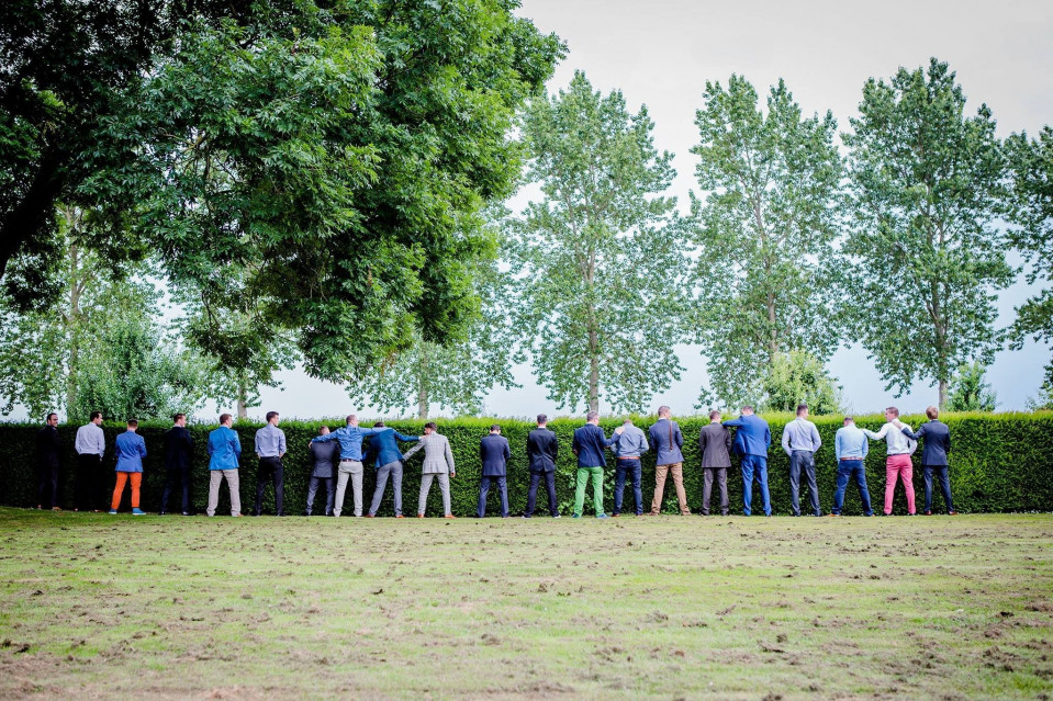 een groep mensen staan in een rij voor een heg