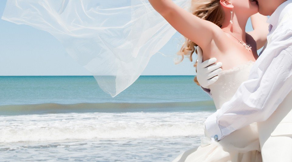 een bruid en bruidegom die kussen op het strand