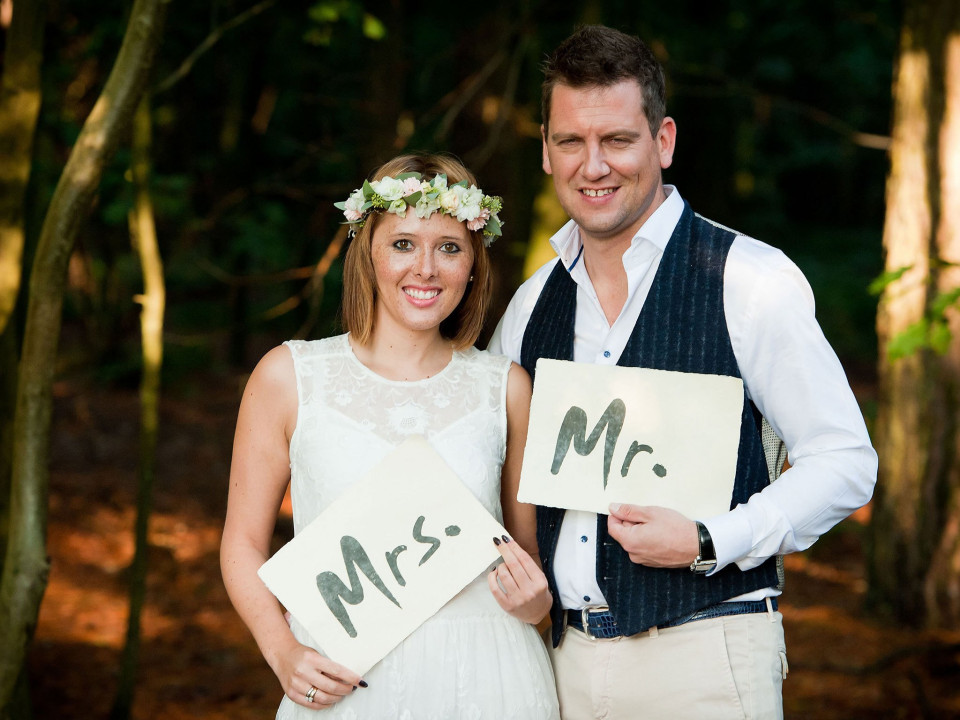 een bruid en bruidegom die borden omhoog houden waarop mr en mrs staat