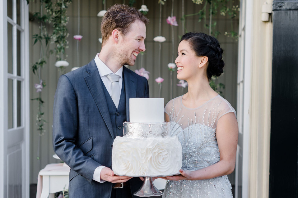 een bruid en bruidegom die een bruidstaart vasthouden