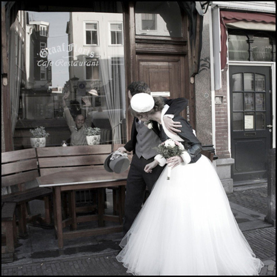 een bruid en bruidegom die kussen voor een gebouw