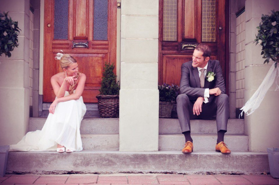 een bruid en bruidegom die op de trappen van een huis zitten