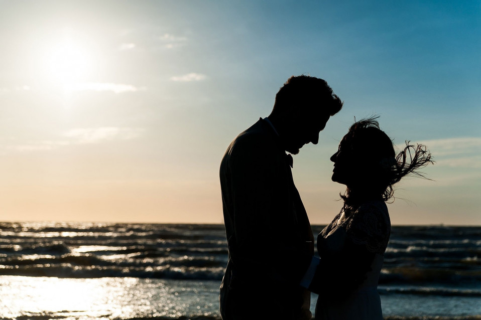 een silhouet van een bruidspaar op het strand