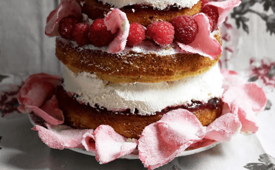 een drielaagse taart met frambozen erop