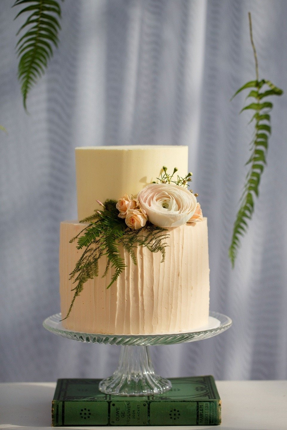 een bruidstaart met bloemen en groen erop