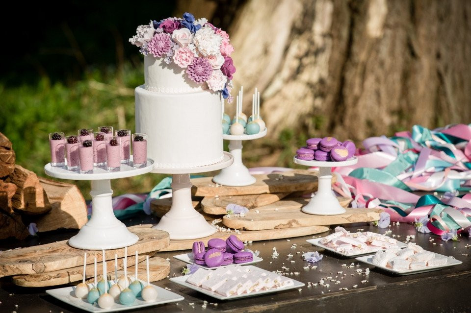 een tafel met een taart, cupcakes en snoep