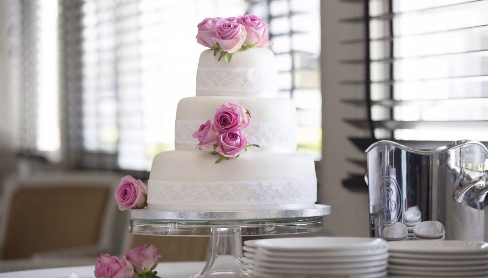 een trouwtaart met roze rozen erop