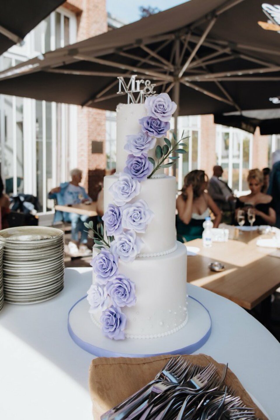 een bruidstaart met paarse bloemen erop