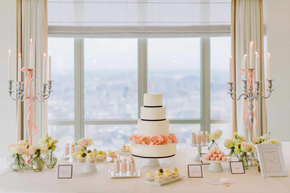 een trouwtaart wordt tentoongesteld op een tafel met kaarsen en bloemen