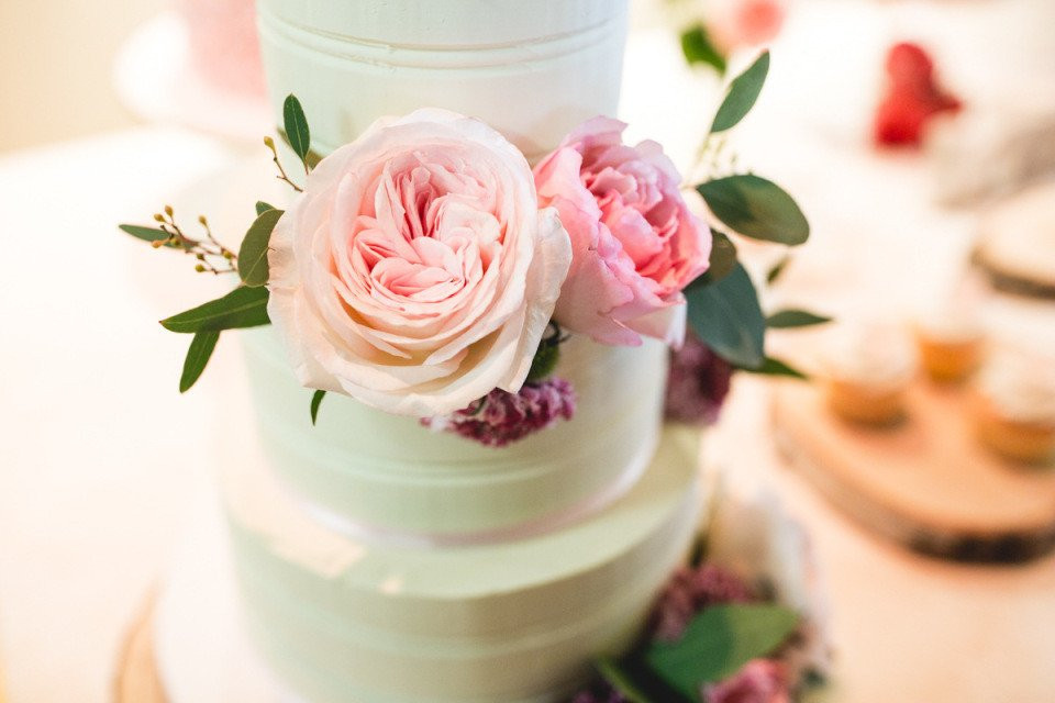 een bruidstaart met roze en groene bloemen