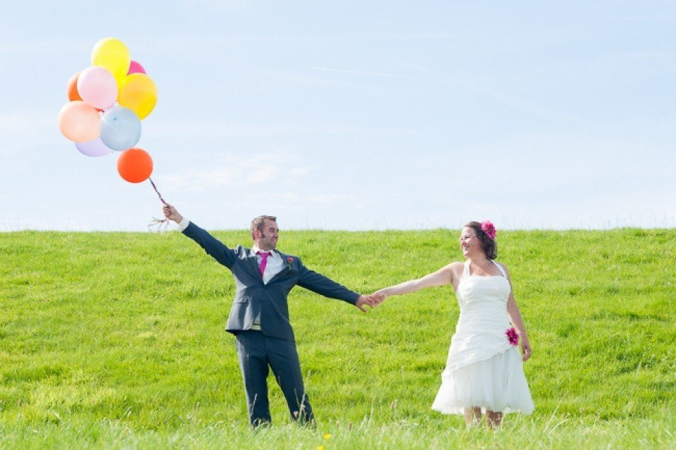 een bruid en bruidegom die ballonnen vasthouden in een veld