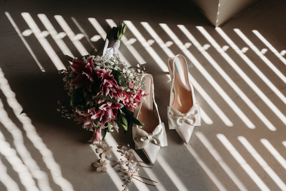 een boeket bloemen naast een paar trouwschoenen
