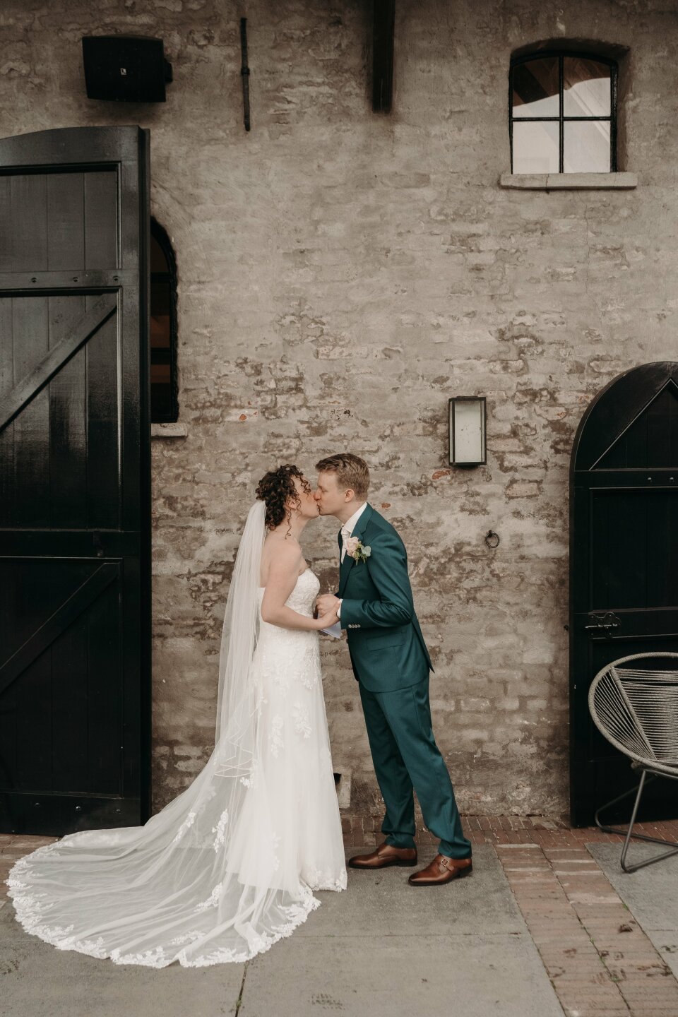 een bruid en bruidegom kussen voor een bakstenen gebouw