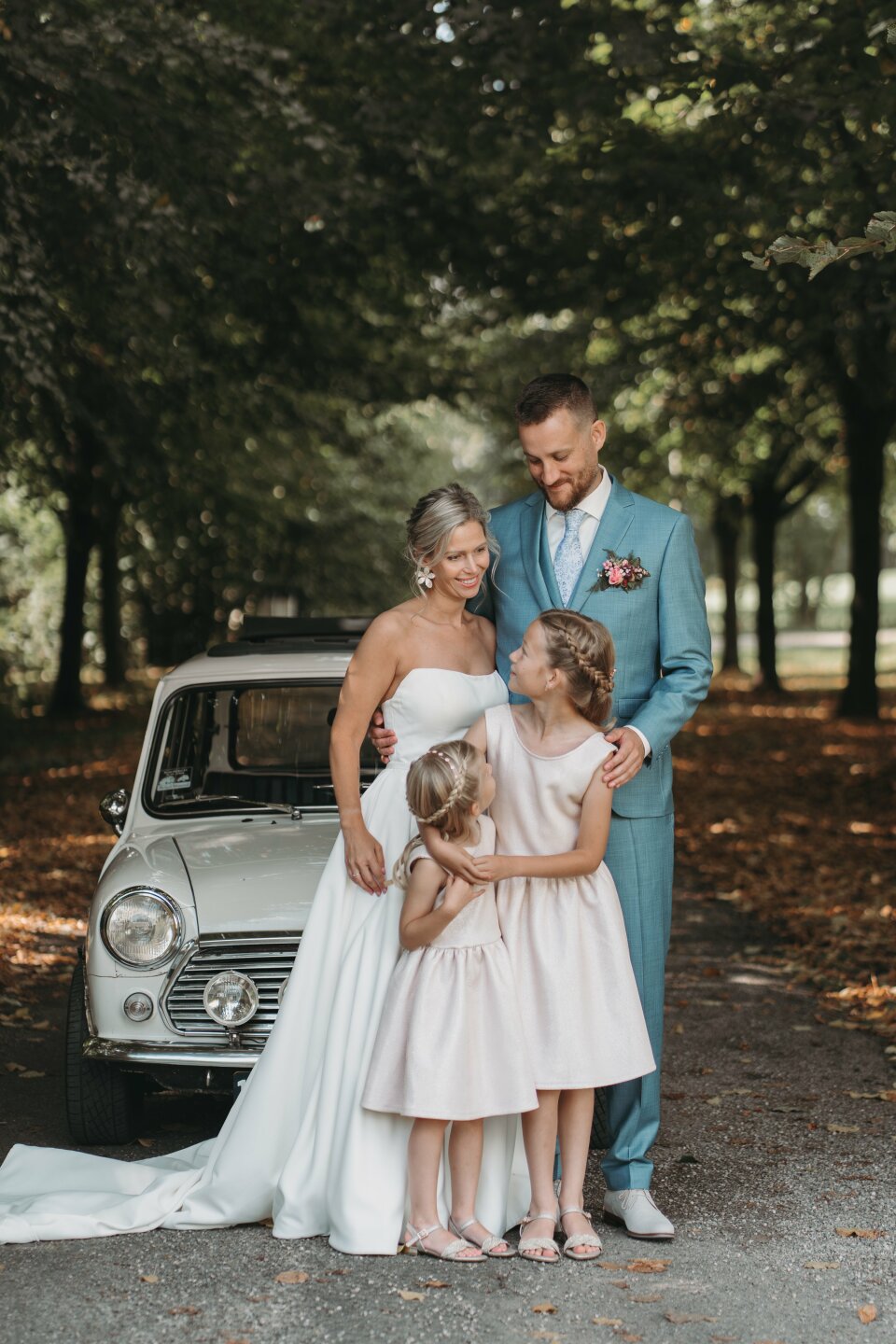 een bruid en bruidegom die naast een klein meisje in een trouwjurk staan