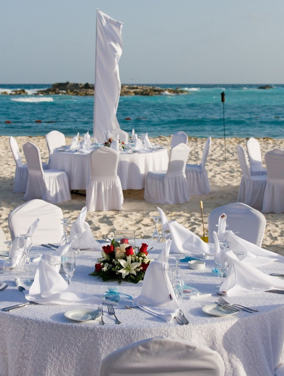 een tafel op het strand opgezet met witte lakens