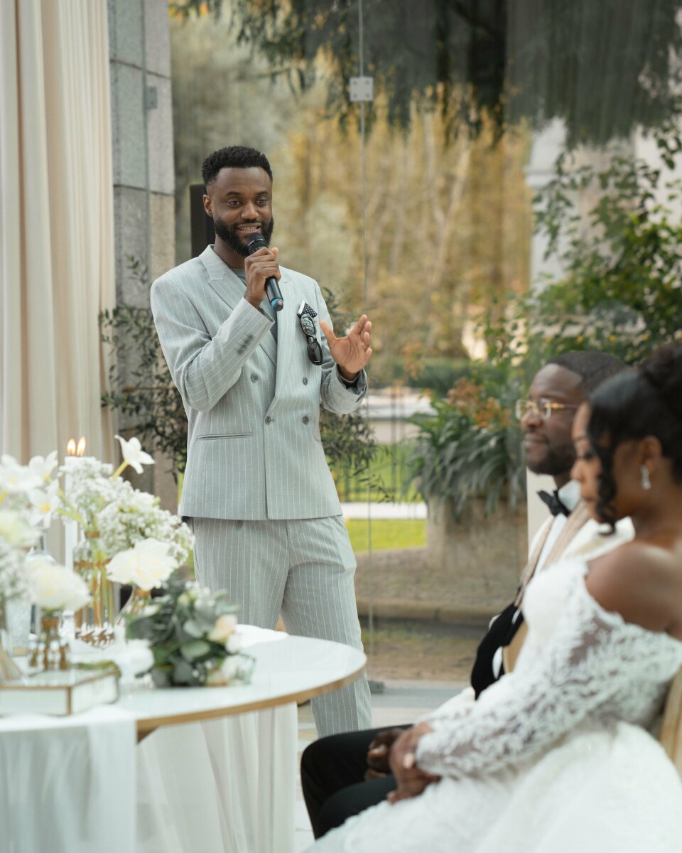 een man in een pak die in een microfoon spreekt