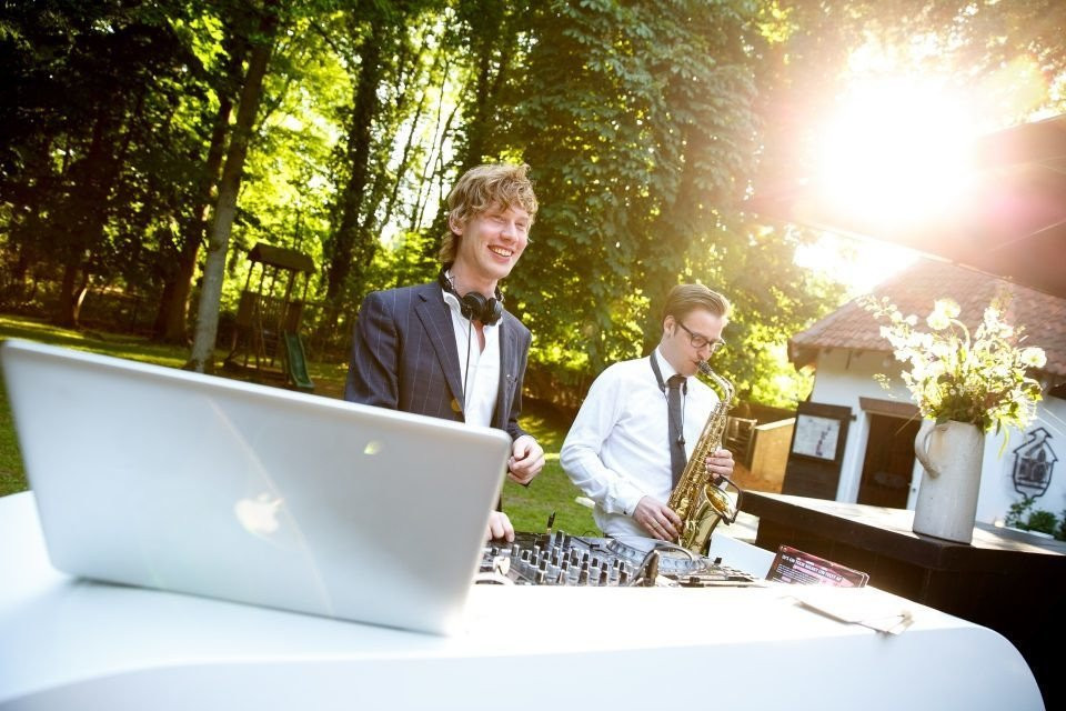 twee mannen in pakken en stropdassen die muziek spelen op een laptop